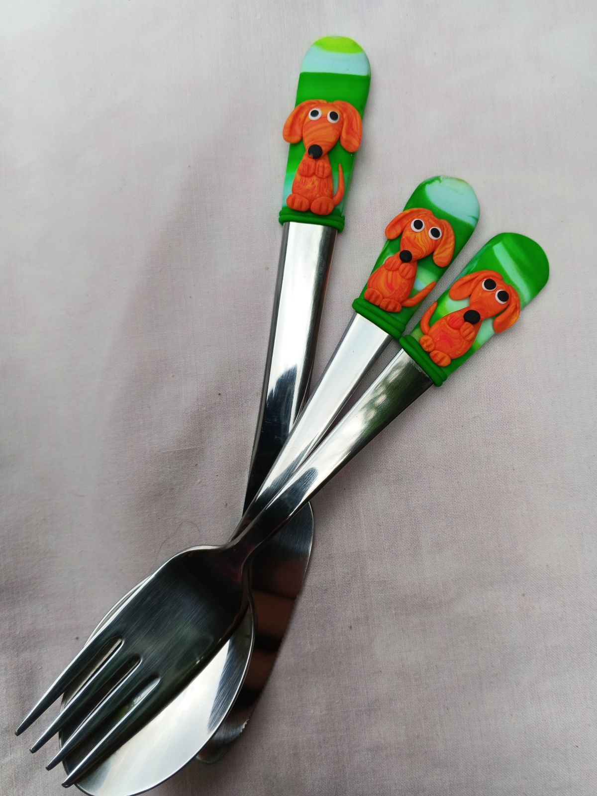 Příbor s oranžovými jezevčíky. Vidlička a lžíce jsou 16cm dlouhé, nůž 18cm s modelovaným veselým jezevčíkem