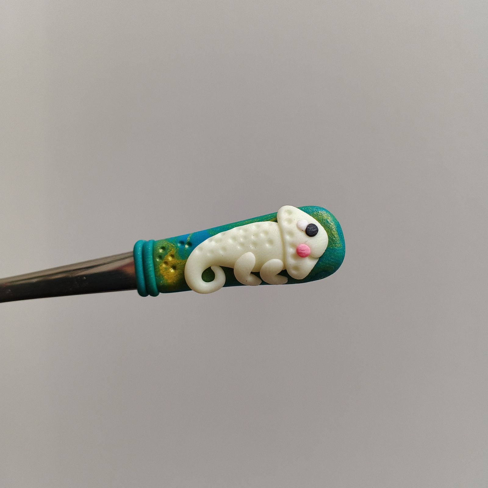 Veselý fosforeskující svítící chameleon na krátké Mocca lžičce - modrozelené pozadí