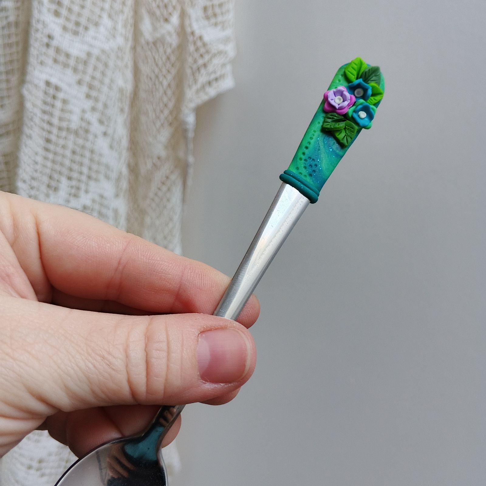 Tmavě zelený podklad s pestrobarevnými květinkami a zelenými lístečky - koktejlová lžička